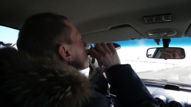 酒后驾车时喝白兰地酒的司机 一个50岁的男人开着车喝着酒瓶 — 图库视频影像