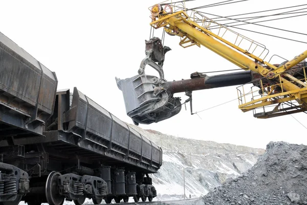 Ekskavatör taşları arabalara yükler..