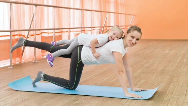 A woman is engaged in sports with a child on her back. — Stock Photo, Image