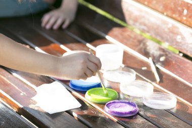 Çocukların elleri fırçayı boyaya batırır..