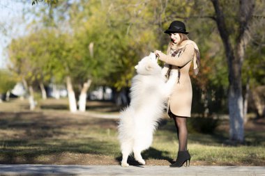 Genç bir kadın parkta köpeğiyle oynuyor..