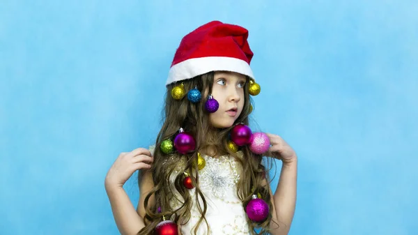 Dívka v Santa Claus klobouk na modrém pozadí. — Stock fotografie
