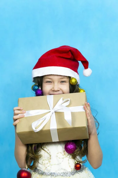Uma criança de chapéu vermelho com um presente de Ano Novo em suas mãos . — Fotografia de Stock