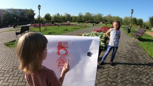 小男孩把他姐姐画成模特儿 一个女孩在她的朋友面前装模作样 他给她画肖像 — 图库视频影像