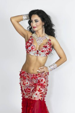 Girl in a red dress for oriental dancing. Brunette beautiful long red dress to perform belly dance on a white background