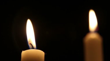 Dini bir etkinlikte bir şamdanda birkaç mum yanar. Karanlık bir arka planda mum alevi.