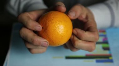 Portakal yetiştirme grafiği üzerinde portakallı eller. Çiftçi işadamı portakal hasadının kar ve giderlerini göz önünde bulundurur..
