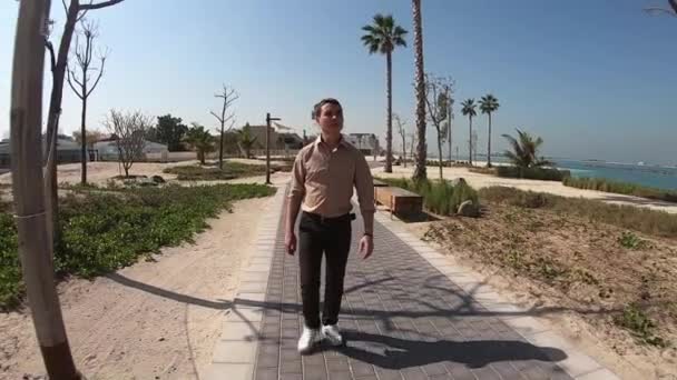 一个成年人沿着海滩走在人行道上 一个35 40岁的男子慢慢地沿着海路走着 环顾四周 — 图库视频影像