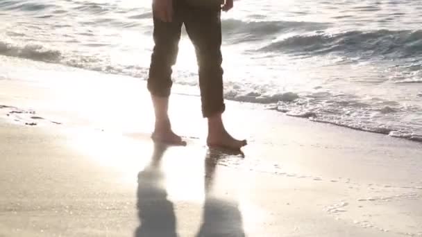 一个穿着长裤赤脚的商人正沿着海滩走着 一个穿着办公室衣服的男人正沿着海滨散步 踩着湿沙和水 — 图库视频影像