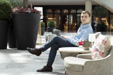 35-40 yaşlarında bir adam süpermarkette alışveriş yapan karısını bekliyor. Bir adam alışveriş merkezinin sandalyesinde dinleniyor..