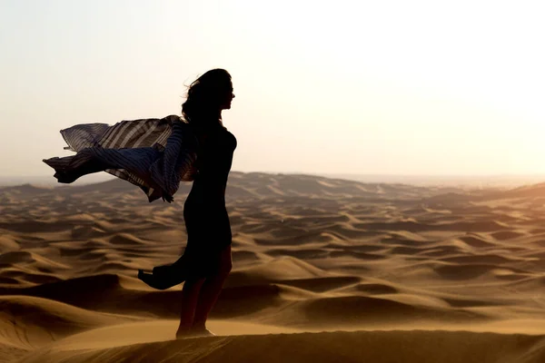 Silhouettes of women at sunset in the desert. A woman stands among the sand dunes in the desert, the sunset shows her powers.