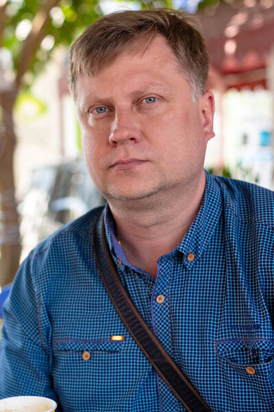 35-40-летний мужчина - одинокий грустный мужчина, сидящий за чашкой кофе в уличном кафе. Одинокий человек сидит в летнем кафе
.