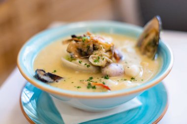 Deniz ürünleri çorbası. Doğu Asya mutfağı. Bir tabak deniz ürünleri çorbası. Kaşıklı bir adam kalamar istiridyeli ıstakoz kabuğu karıştırıyor..