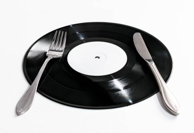Beyaz arka planda gümüş bıçak ve çatal, müzik ve yiyecek konseptiyle plaka şeklinde 25 santimlik siyah plak kaydı.