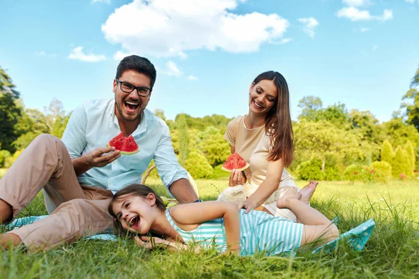 Família em Park. Jovens pais felizes e criança relaxante ao ar livre — Fotografia de Stock