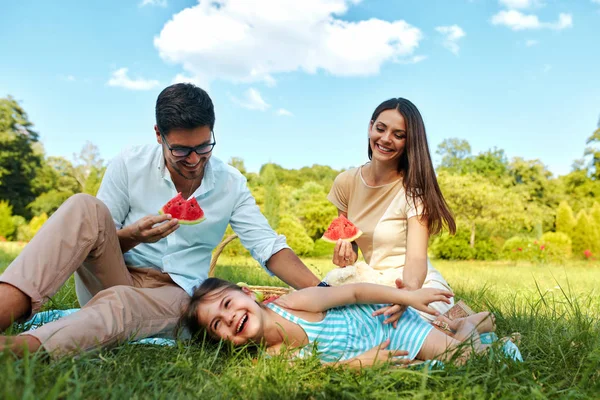 Família em Park. Jovens pais felizes e criança relaxante ao ar livre — Fotografia de Stock