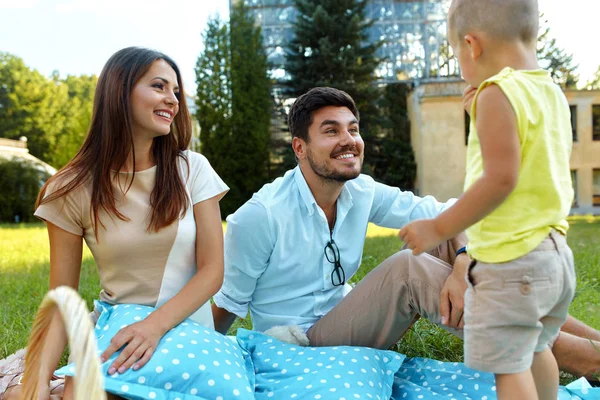 Familia en el parque. Padres jóvenes felices y niños relajándose al aire libre — Foto de Stock