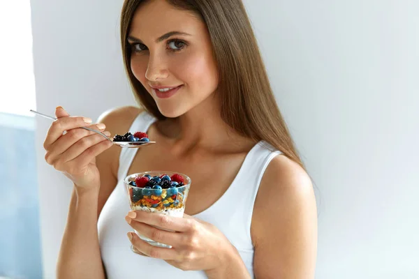 Mulher comendo iogurte, bagas e aveia para o café da manhã saudável — Fotografia de Stock