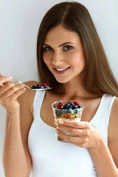 Портрет улыбающейся женщины, поедающей йогурт с овсянкой и ягодами — стоковое фото