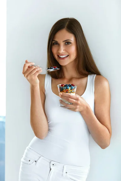 Retrato de una mujer sonriente comiendo yogur con avena y bayas —  Fotos de Stock