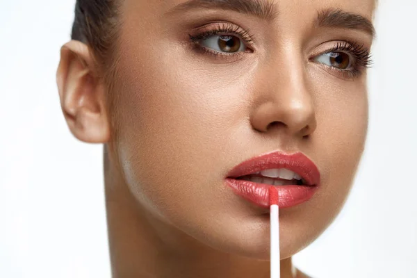 Hermosa mujer haciendo maquillaje usando brillo de labios en los labios. Cosméticos — Foto de Stock