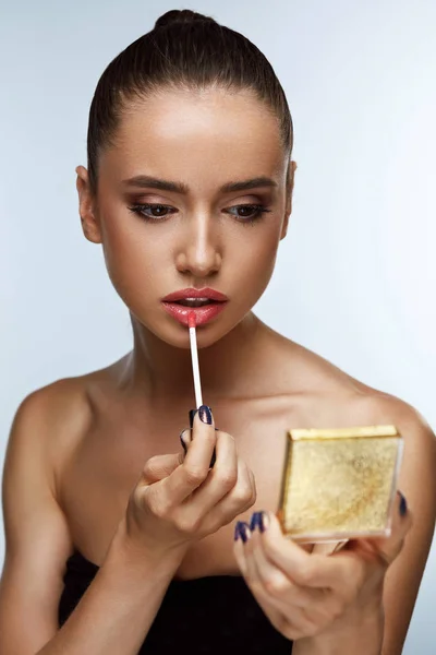 Hermosa mujer haciendo maquillaje poniendo brillo de labios en los labios. Cosméticos — Foto de Stock