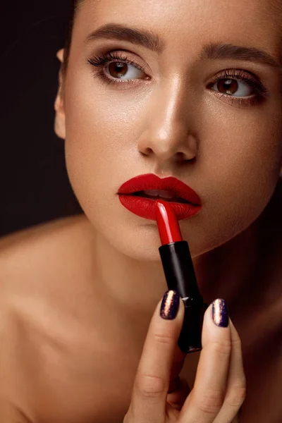 Schöne Frau mit leuchtend roten Lippen und Lippenstift in der Hand — Stockfoto