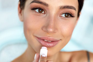 Beautiful Woman With Beauty Face Applies Balm On Lips. Skin Care clipart