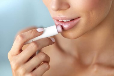 Beautiful Woman Applying Lip Protector On Lips Skin. Beauty clipart