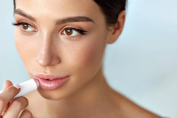 Mooie vrouw met schoonheid gezicht past balsem op de lippen. Huidverzorging — Stockfoto