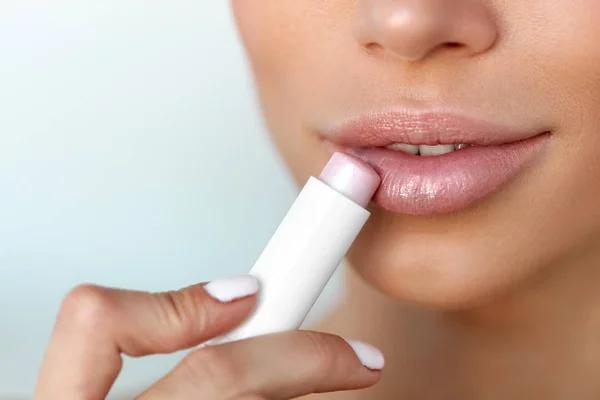 Hermosa mujer que aplica protector labial en la piel de los labios. Belleza — Foto de Stock