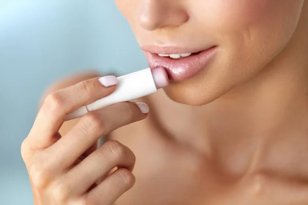 Smuk kvinde, der anvender Lip Protector på læber hud. Skønhed - Stock-foto
