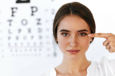Closeup Of Smiling Young Woman In Front Of Visual Eye Test Board clipart