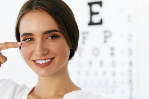Fechar-se de sorrir jovem mulher na frente da placa de teste de olho visual — Fotografia de Stock
