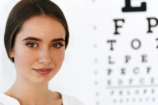 Vision. Belle femme avec tableau de test visuel des yeux sur fond — Photo