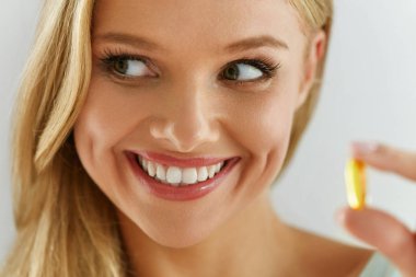 Vitamin ve ek. Balık yağı kapsül tutan güzel kadın