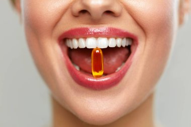 Dişlerinde hap olan güzel bir kadın ağzı. Kız vitamin alıyor.