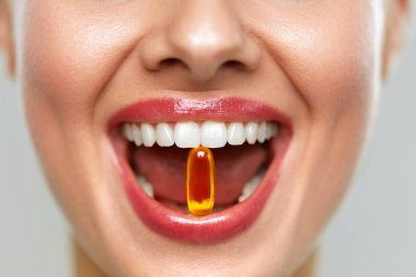 Dişlerinde hap olan güzel bir kadın ağzı. Kız vitamin alıyor.