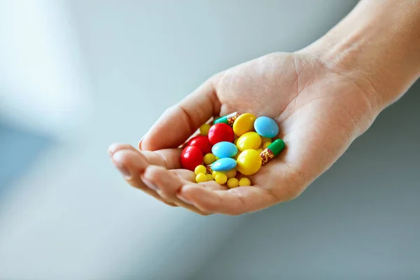 Vitaminas e suplementos. Mão feminina com comprimidos coloridos — Fotografia de Stock