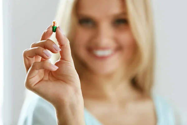 Vitaminas e suplementos alimentares. Mulher bonita com pílula na mão — Fotografia de Stock