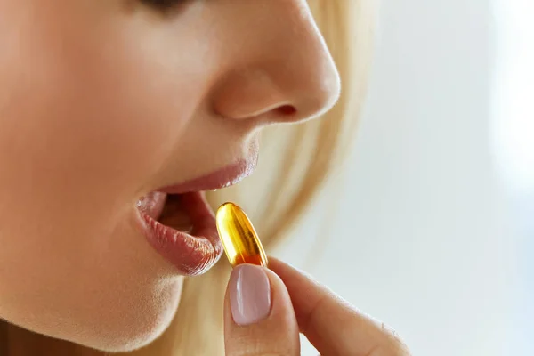 Zbliżenie piękna kobieta biorąc kapsułki oleju ryb w ustach — Zdjęcie stockowe