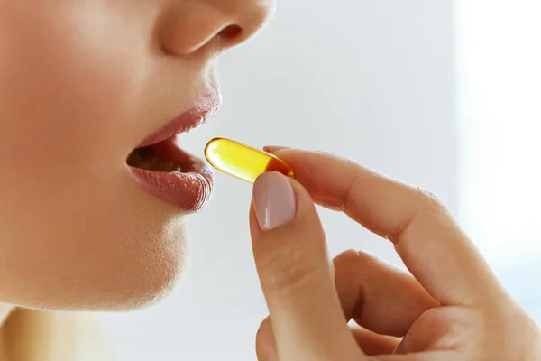 Primer plano de la hermosa mujer tomando aceite de pescado cápsula en la boca — Foto de Stock