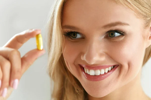 Vitamina y suplemento. Hermosa mujer sosteniendo aceite de pescado cápsula — Foto de Stock