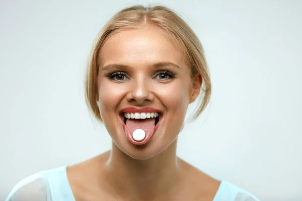 Mulher sorridente bonita tomando remédio, segurando pílula na língua — Fotografia de Stock
