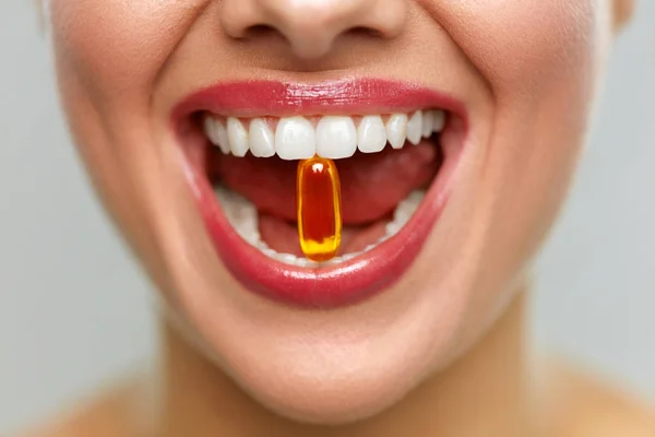 Hermosa boca de mujer con píldora en dientes. Chica tomando vitaminas — Foto de Stock