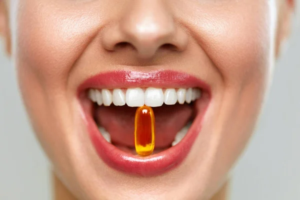 Hermosa boca de mujer con píldora en dientes. Chica tomando vitaminas — Foto de Stock