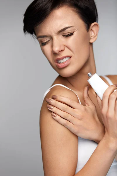 Tratamiento de lesiones. Hermosa mujer con dolor en los brazos, aplicación de crema — Foto de Stock