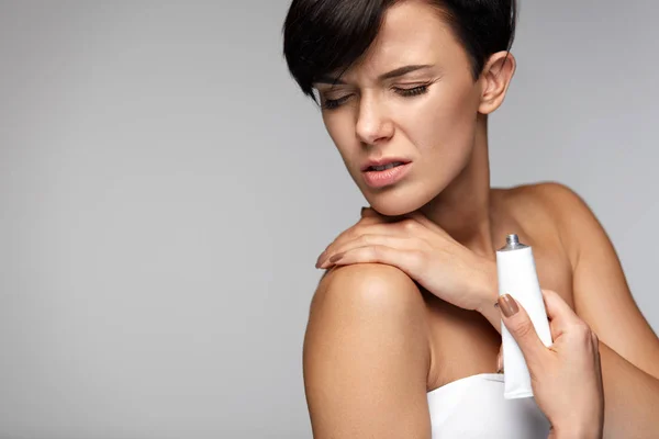 Verletzungsbehandlung. schöne Frau mit Nackenschmerzen cremt sich ein — Stockfoto