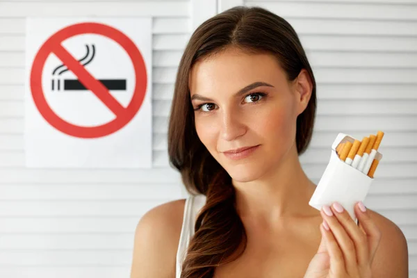 Schöne Frau mit Zigarettenschachtel und Rauchverbotsschild — Stockfoto