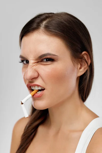 Cigaretta a szájban és a fintor az arcán lány portréja — Stock Fotó